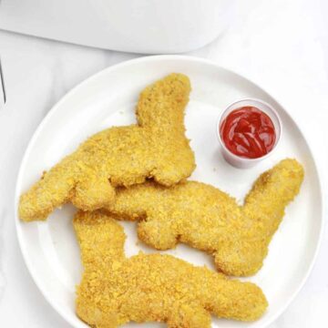 3 pieces dinosaur nuggets served on a plate with ketchup.