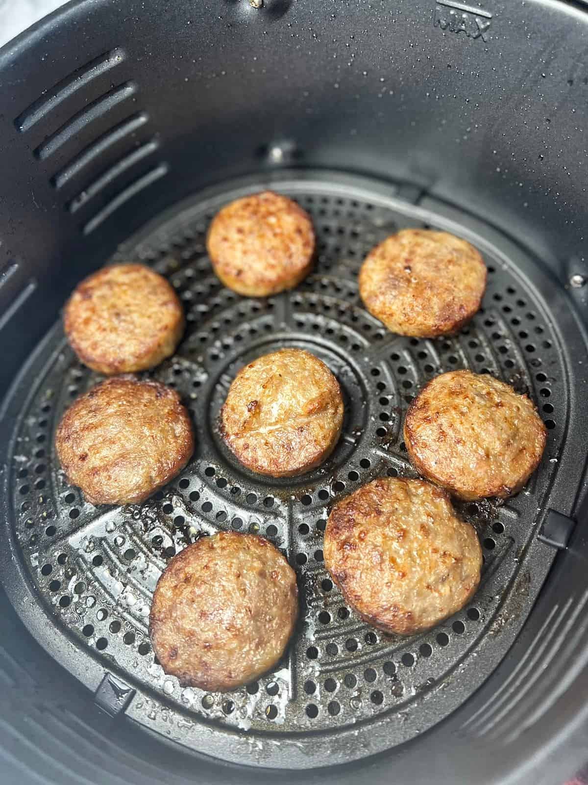 cooked sausage patties displayed in air fryer basket.