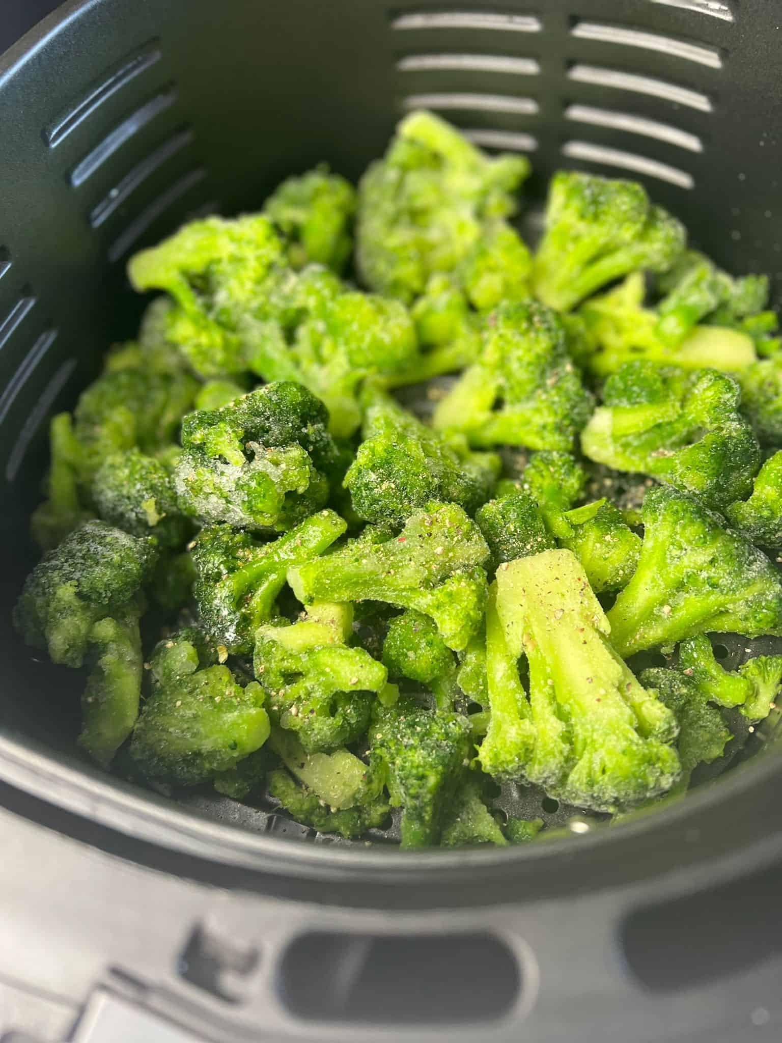 frozen broccoli in air fryer basket.
